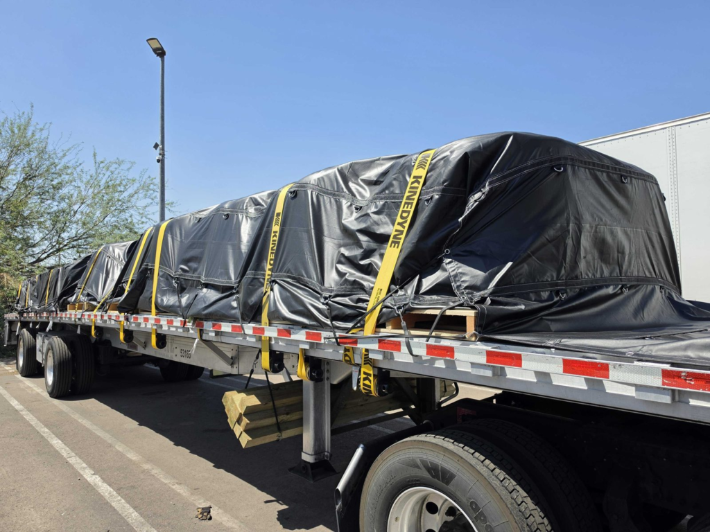 Black tarp and yellow straps securing a load on a flatbed trailer