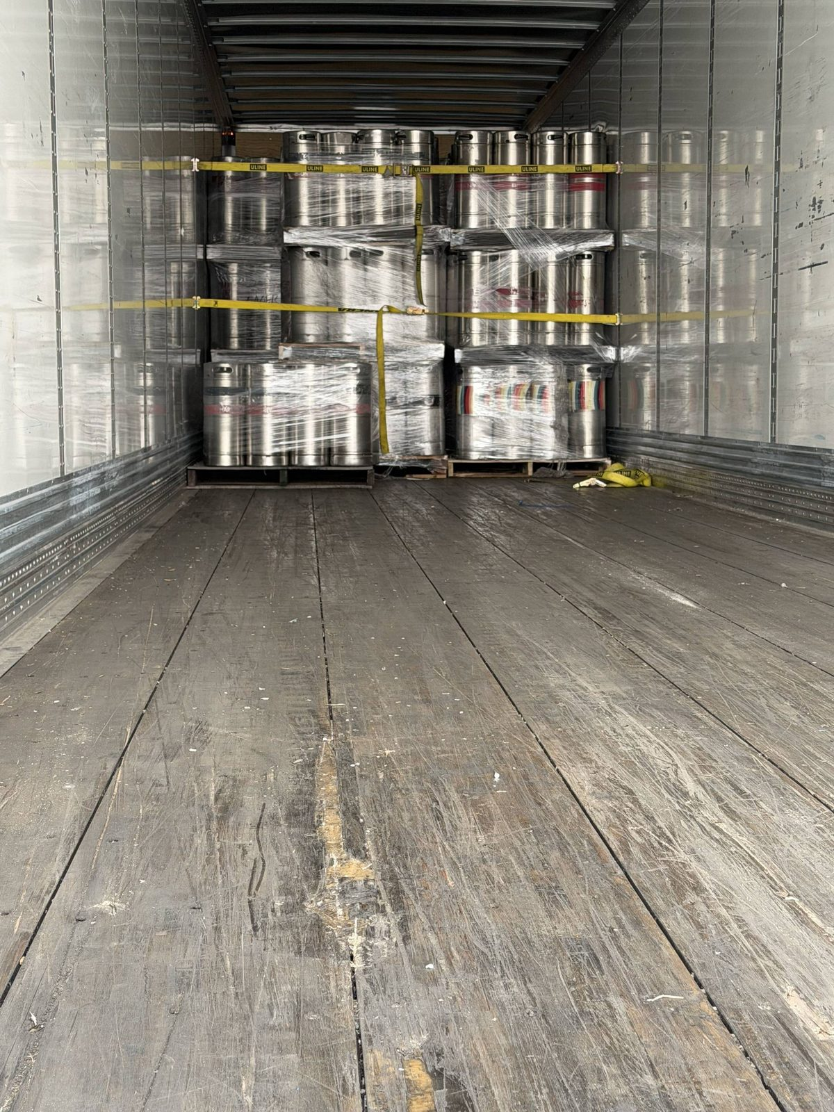 Shrink-wrapped pallets strapped at the front of an empty enclosed trailer